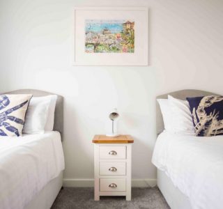 Beach Haven twin room with singular bedside cabinet with bedside lamp.