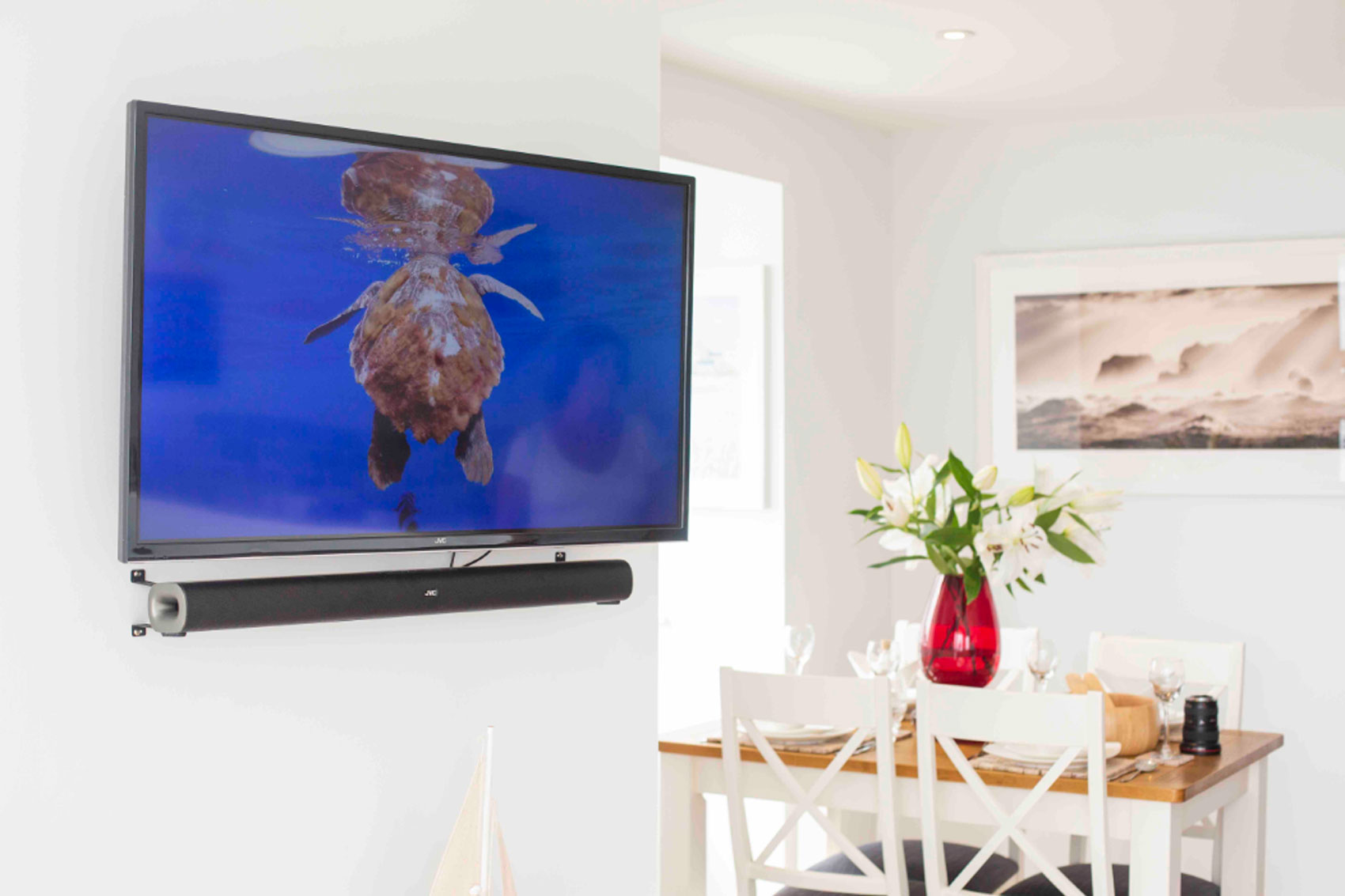 Beach Haven wall mounted tv and soundbar in living area. Open plan dining area in the background.