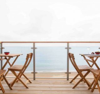 View of Beach Havens balcony with 2 tables and 4 chairs overlooking the sea