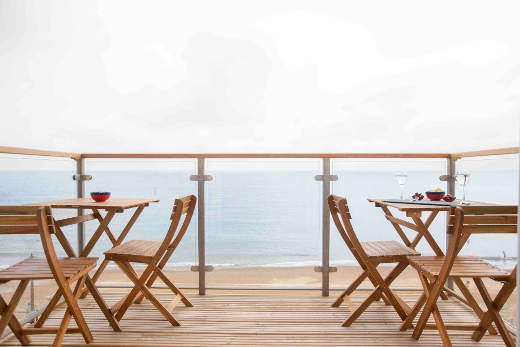 View of Beach Havens balcony with 2 tables and 4 chairs overlooking the sea